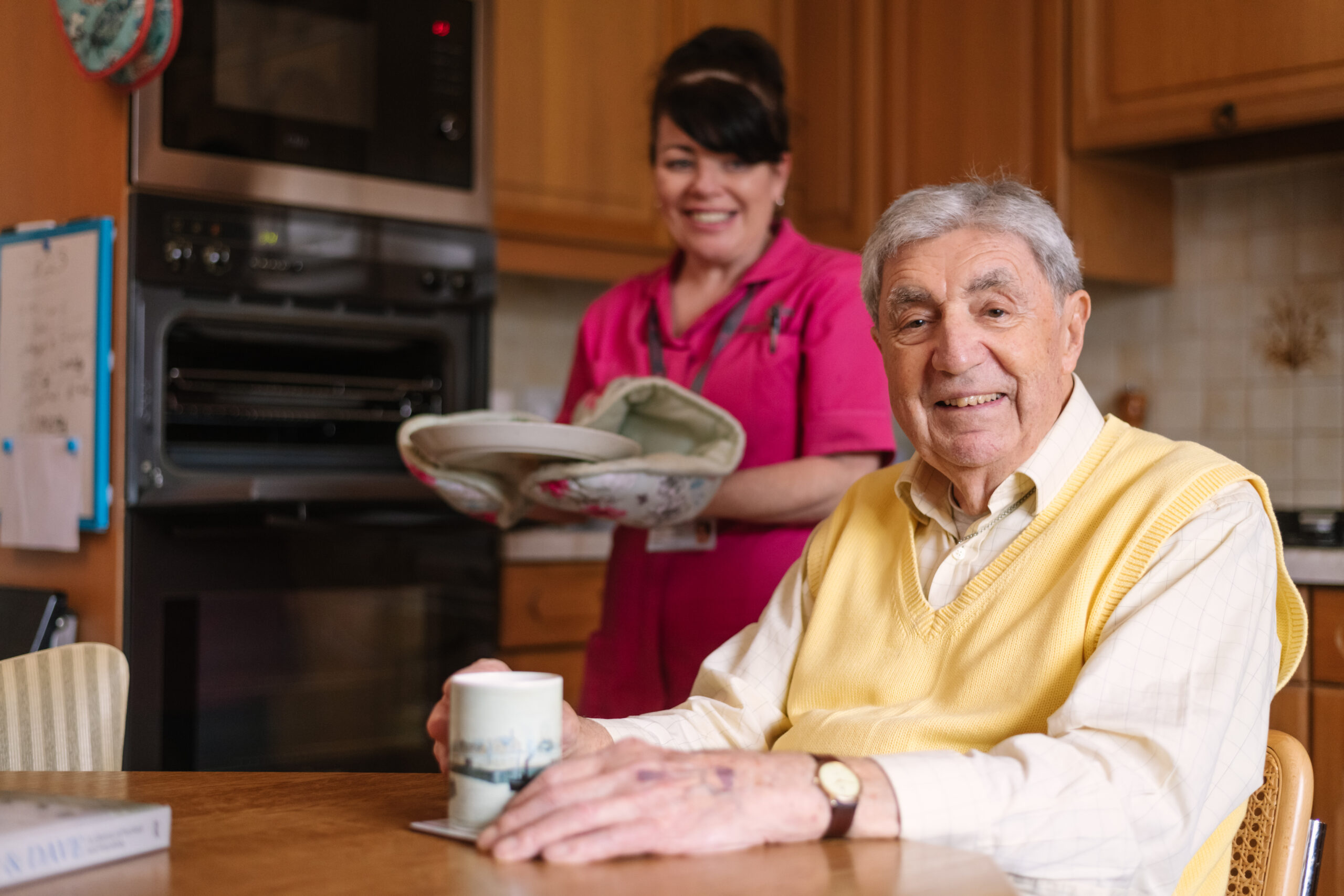 Carer preparing meal for elderly client